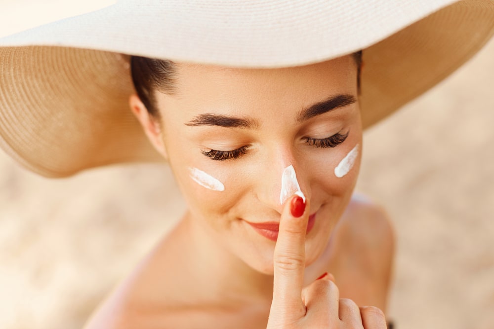 Beautiful Young woman with sun cream on face